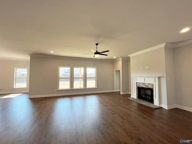 unfurnished living room featuring ceiling fan, a stone fireplace, dark wood-style flooring, and baseboards