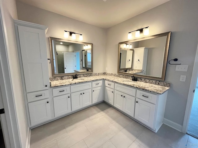 full bath with double vanity, a sink, and baseboards