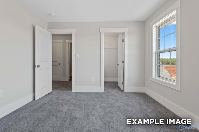 unfurnished bedroom featuring carpet floors, baseboards, and a walk in closet