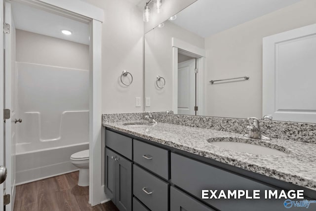 bathroom featuring double vanity, a sink, toilet, and wood finished floors