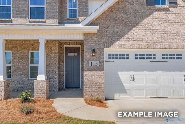 property entrance with an attached garage and brick siding