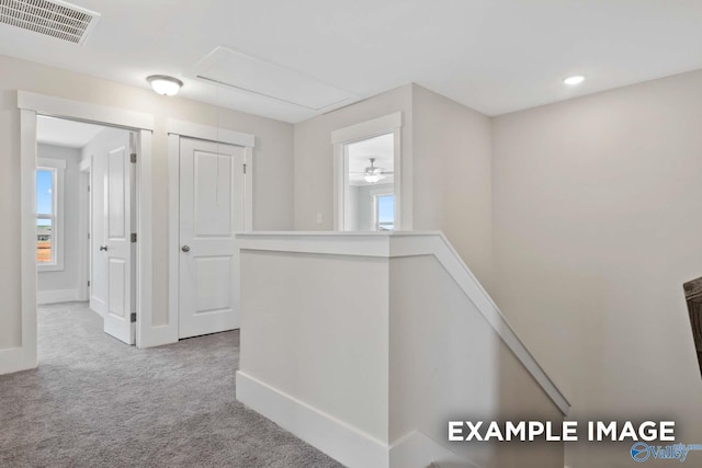 hall featuring carpet floors, visible vents, attic access, an upstairs landing, and baseboards