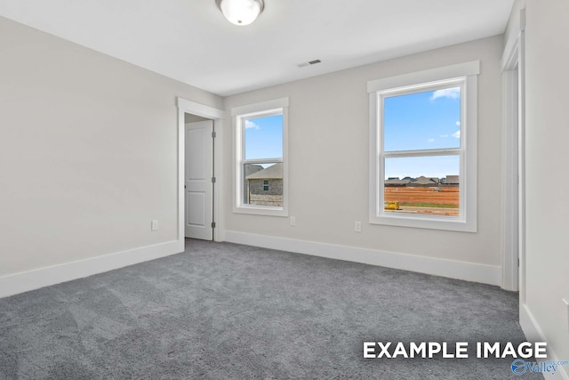 carpeted empty room featuring visible vents and baseboards