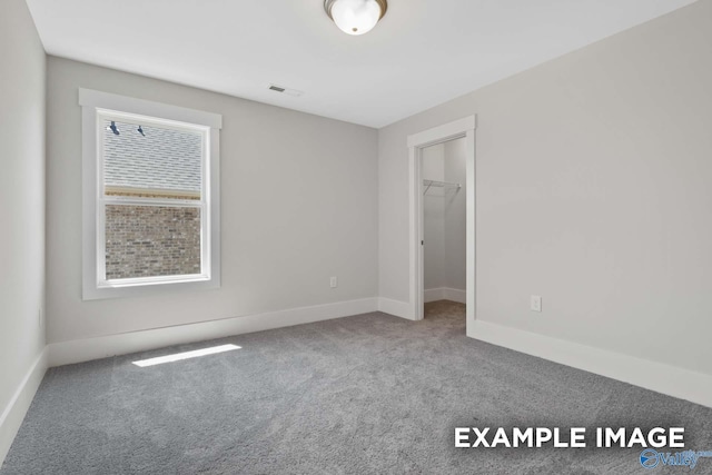 unfurnished bedroom featuring baseboards, a spacious closet, visible vents, and carpet flooring