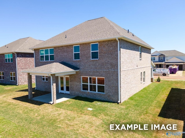 rear view of house featuring french doors, brick siding, a patio, a shingled roof, and a lawn