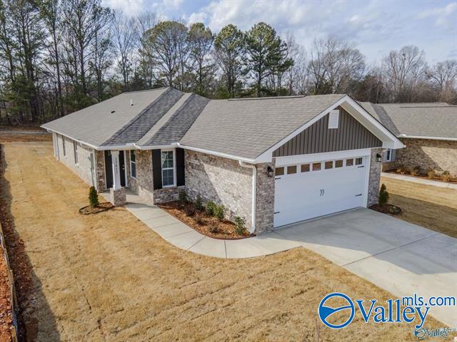 single story home featuring driveway, board and batten siding, stone siding, an attached garage, and a front yard