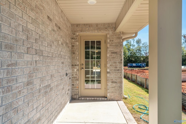 entrance to property featuring fence and brick siding