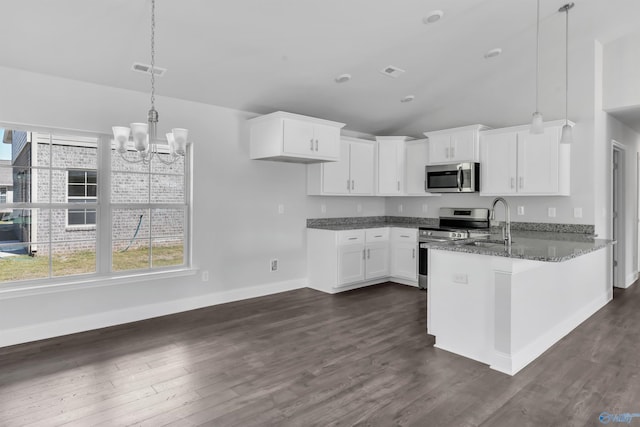 kitchen featuring a peninsula, dark stone countertops, a sink, stainless steel appliances, and a notable chandelier