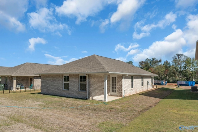 view of side of home with a lawn, a patio area, brick siding, fence, and a shingled roof
