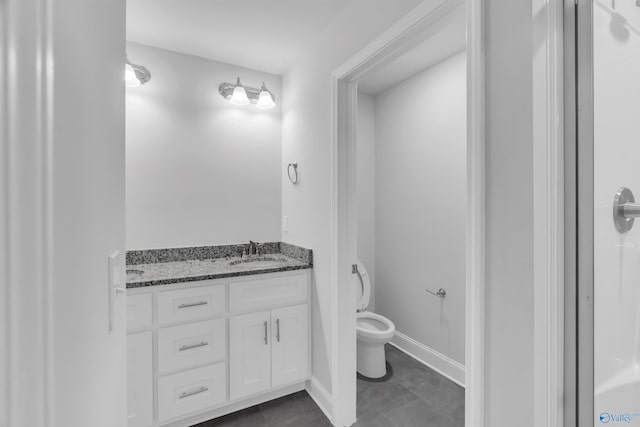 full bathroom with a sink, toilet, double vanity, and baseboards