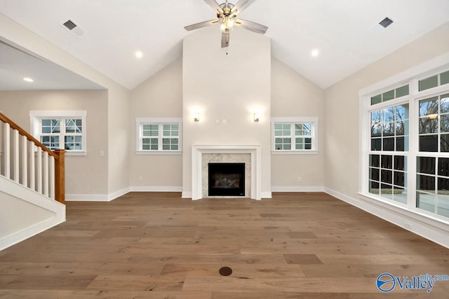 unfurnished living room with visible vents, wood finished floors, a high end fireplace, baseboards, and stairs