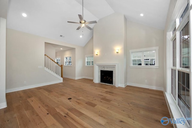 unfurnished living room featuring visible vents, hardwood / wood-style flooring, a high end fireplace, stairway, and baseboards