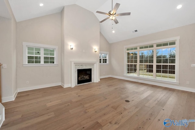 unfurnished living room with a ceiling fan, wood finished floors, visible vents, high vaulted ceiling, and a high end fireplace