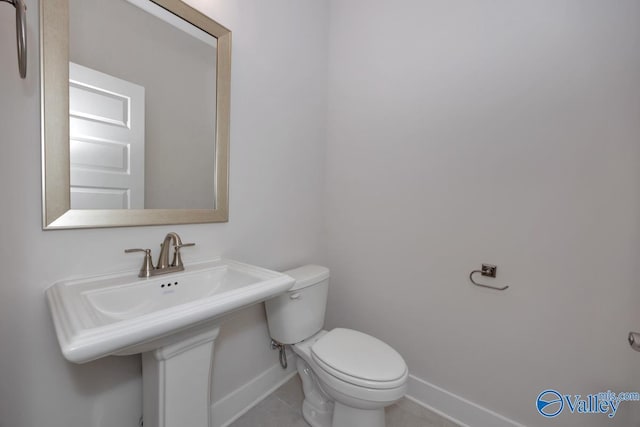 half bathroom featuring tile patterned floors, toilet, and baseboards