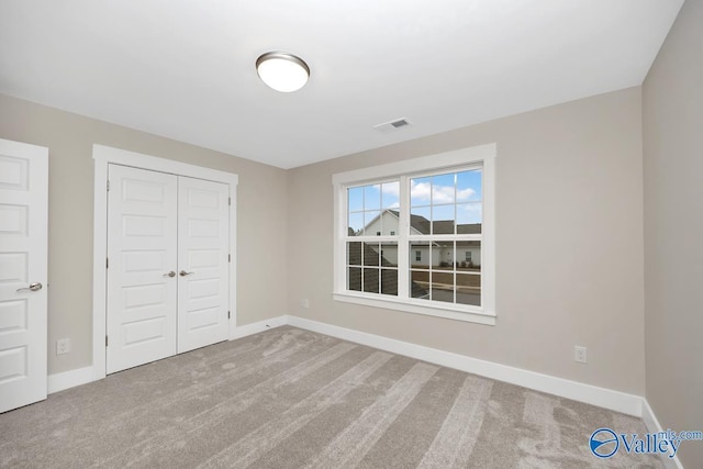 unfurnished bedroom with a closet, visible vents, baseboards, and carpet floors