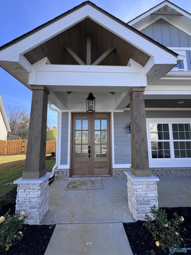 property entrance featuring fence, french doors, and board and batten siding