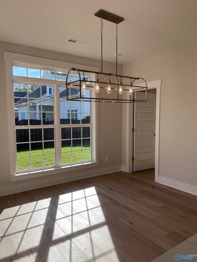 unfurnished dining area featuring wood finished floors, baseboards, and a wealth of natural light