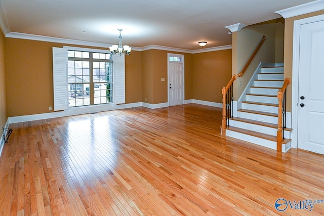 interior space with an inviting chandelier, ornamental molding, and hardwood / wood-style floors