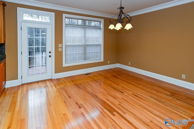 unfurnished dining area with an inviting chandelier, ornamental molding, and light hardwood / wood-style floors