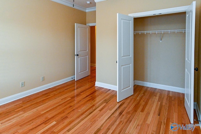 unfurnished bedroom with crown molding, light hardwood / wood-style floors, and a closet