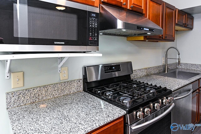 kitchen with light stone counters, stainless steel appliances, and sink