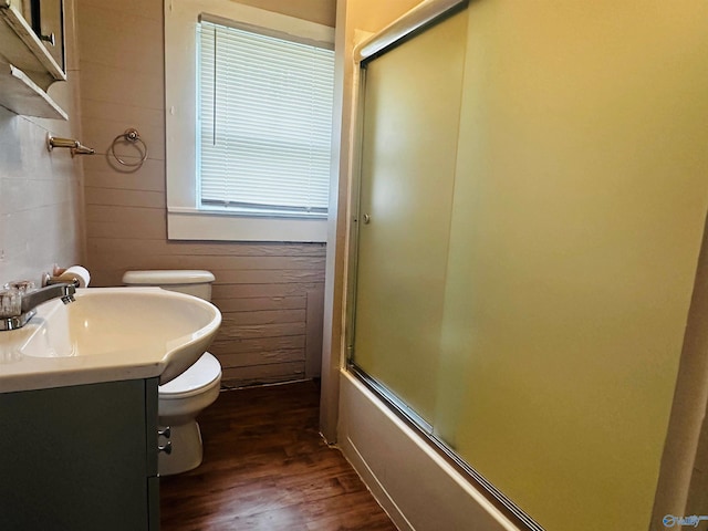 full bathroom with bath / shower combo with glass door, vanity, toilet, and hardwood / wood-style floors