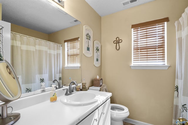 full bathroom with visible vents, toilet, vanity, a textured ceiling, and baseboards