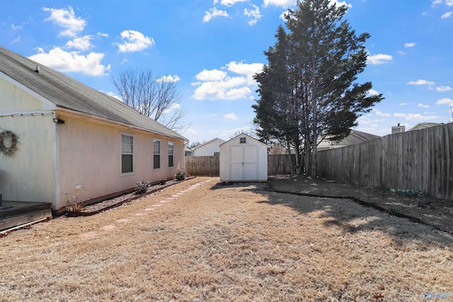 view of yard with a storage shed, a fenced backyard, and an outbuilding