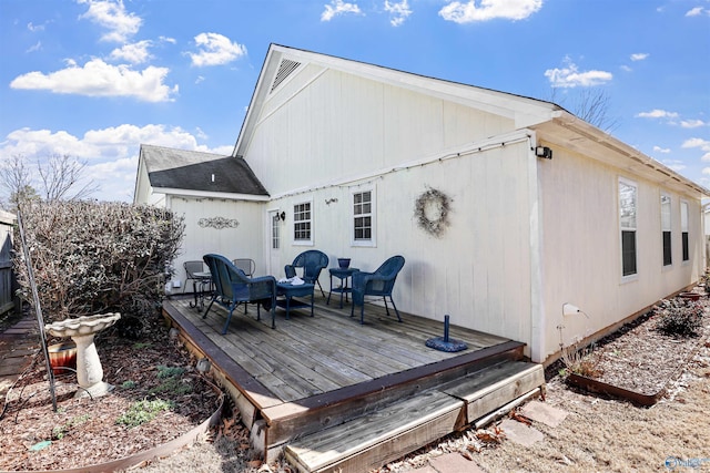 back of property featuring a shingled roof and a deck