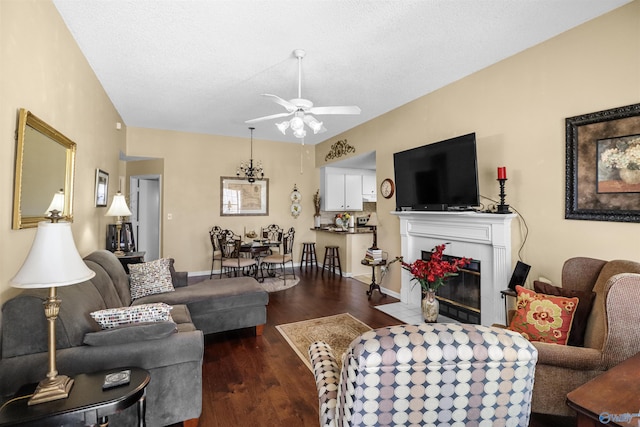 living room featuring dark wood-style floors, ceiling fan, a textured ceiling, a tile fireplace, and baseboards