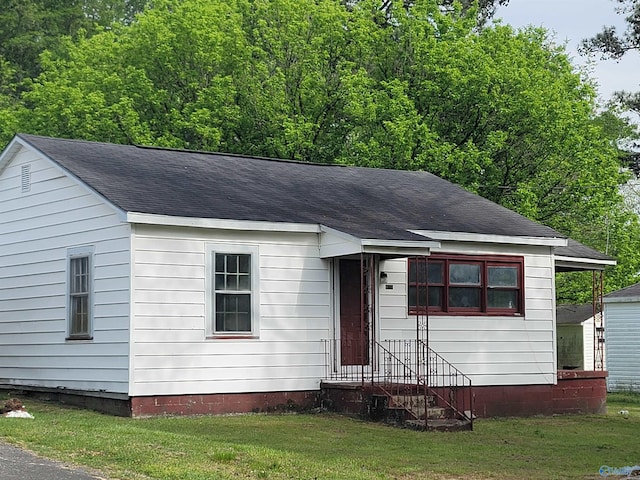 view of front of home with a shingled roof and a front yard