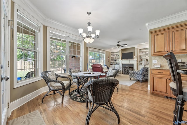 23245 Piney Creek Dr, Athens, AL 35613 - dining space with crown molding, a chandelier, a fireplace, a ceiling fan, and light wood-style flooring
