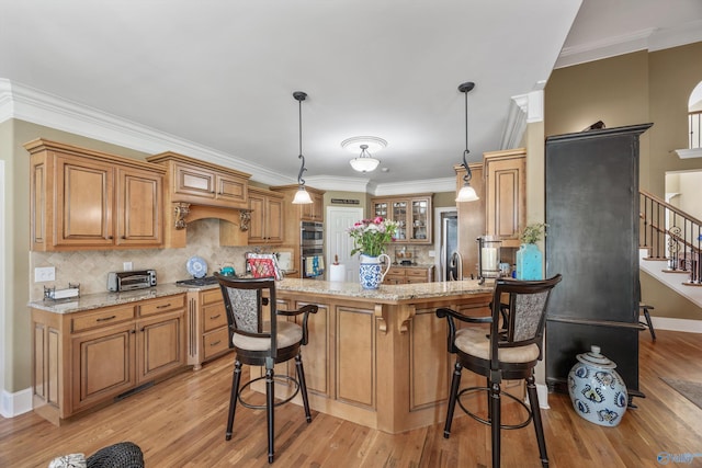 23245 Piney Creek Dr, Athens, AL 35613 - kitchen with light stone counters, light wood finished floors, tasteful backsplash, a kitchen breakfast bar, and brown cabinetry
