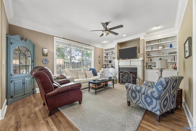 23245 Piney Creek Dr, Athens, AL 35613 - living area featuring a ceiling fan, wood finished floors, crown molding, a fireplace with raised hearth, and baseboards