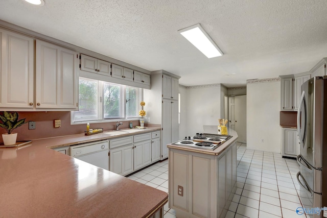 kitchen featuring white appliances, sink, light tile patterned floors, a textured ceiling, and a center island