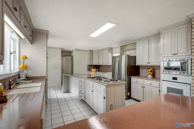 kitchen featuring appliances with stainless steel finishes, white cabinets, sink, a textured ceiling, and light tile patterned flooring