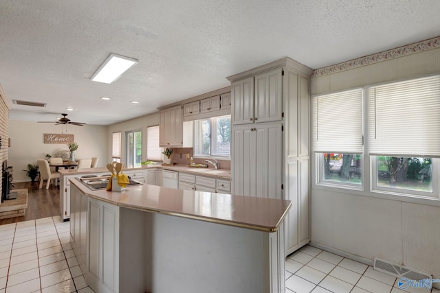 kitchen with stainless steel gas cooktop, light tile patterned flooring, a textured ceiling, and ceiling fan