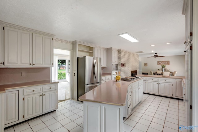 kitchen featuring light tile patterned flooring, a center island, ceiling fan, and stainless steel appliances