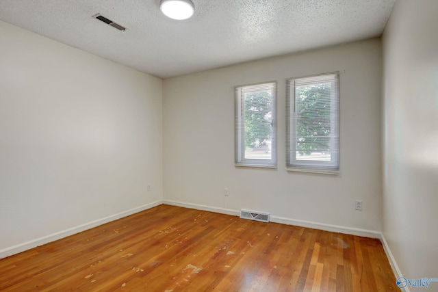 spare room with a textured ceiling and hardwood / wood-style flooring