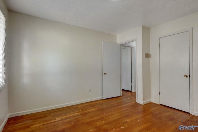 unfurnished bedroom featuring wood-type flooring and a textured ceiling