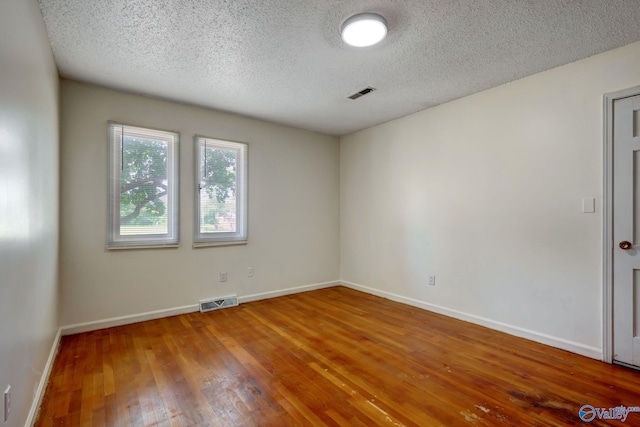 unfurnished room with a textured ceiling and hardwood / wood-style floors