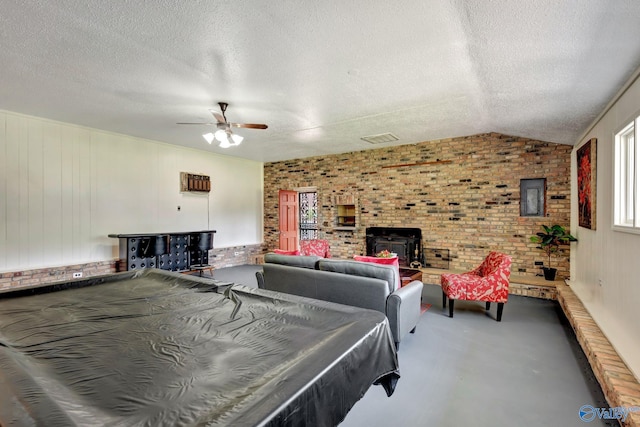 bedroom featuring vaulted ceiling, pool table, a textured ceiling, a brick fireplace, and brick wall