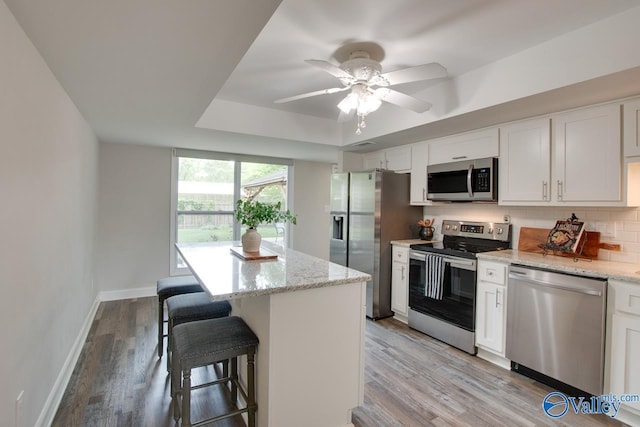 1908 Spanish Oaks Dr SE, Huntsville, AL 35803 - kitchen featuring stainless steel appliances, a kitchen breakfast bar, white cabinetry, tasteful backsplash, and a kitchen island