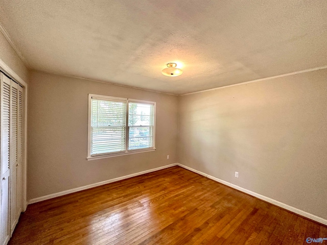 unfurnished bedroom featuring a textured ceiling, dark hardwood / wood-style floors, and a closet