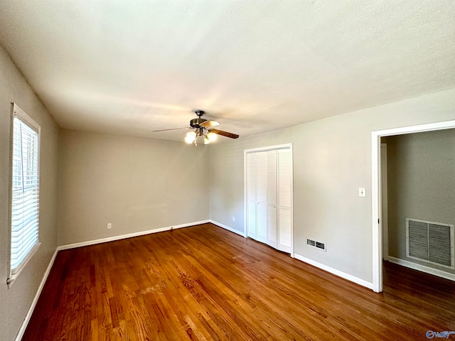 unfurnished bedroom with dark wood-type flooring, a closet, ceiling fan, and a textured ceiling