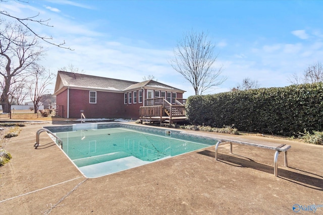 view of swimming pool with a wooden deck and a diving board