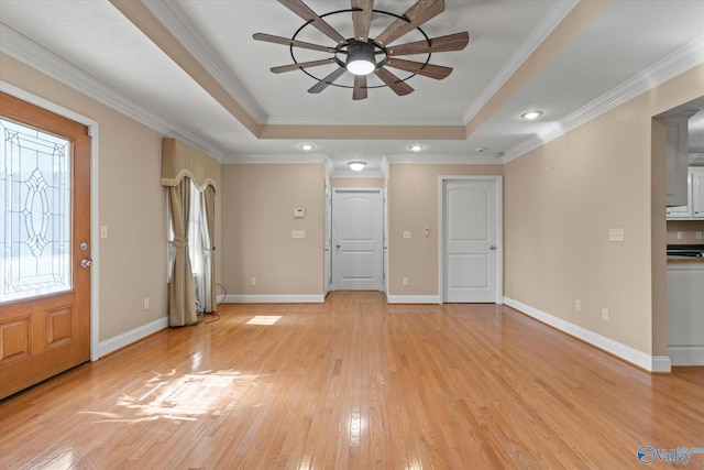 entrance foyer with light hardwood / wood-style floors, a tray ceiling, and ornamental molding