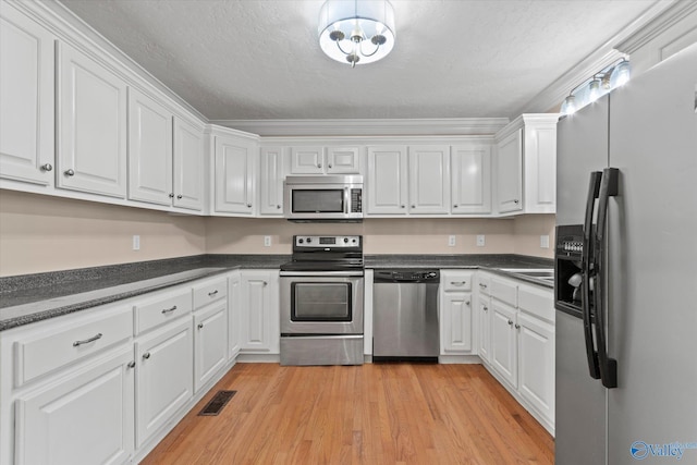 kitchen with a textured ceiling, white cabinets, light hardwood / wood-style flooring, and stainless steel appliances