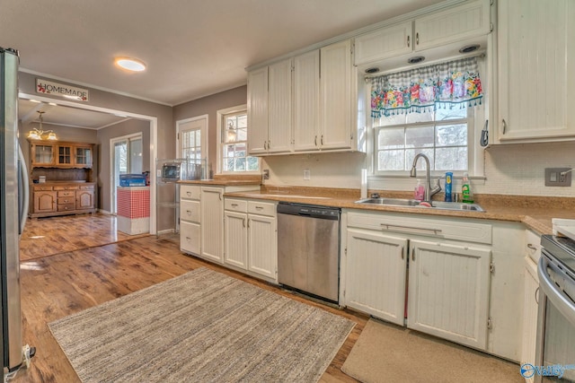 kitchen with stainless steel appliances, light countertops, a sink, and light wood-style flooring