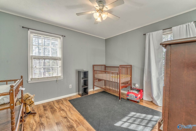 bedroom with baseboards, wood finished floors, a ceiling fan, and crown molding